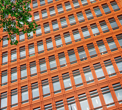 Close-up on an orange skyscraper building tower with multiple business offices apartments. This is a concept for market study, economy and trends for real estate properties.