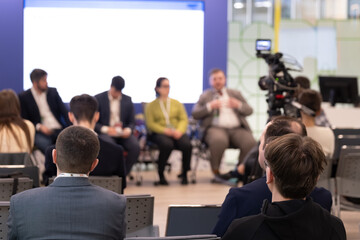 Obraz premium Business panel discussion in conference room, audience listens to professional speakers, camera records session, corporate networking and collaboration atmosphere.
