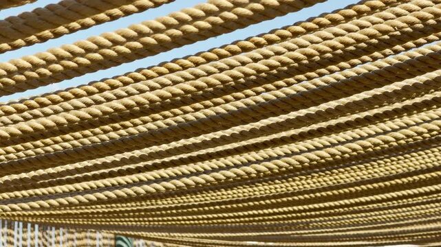A thick layer of rustic ropes stretches tightly overhead to provide cooling shade. The dense, natural pattern creates a cozy and sheltered feeling under the bright summer sky.