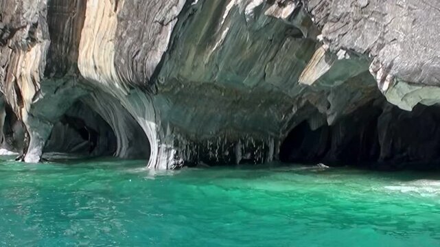 Witness the stunning Marble Caves of Patagonia. Turquoise water flows around exquisitely carved marble pillars, revealing a mesmerizing natural masterpiece during a sunny day.