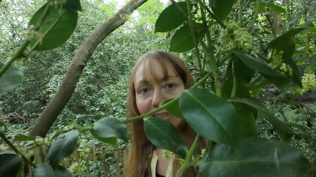 Woman hiding behind tree leaves and enjoying being in nature