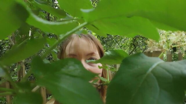 Woman hiding behind tree leaves and enjoying being in nature