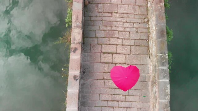 Aerial overhead view of Devils Bridge, Lucca. Red heart shape umbrella on the bridge