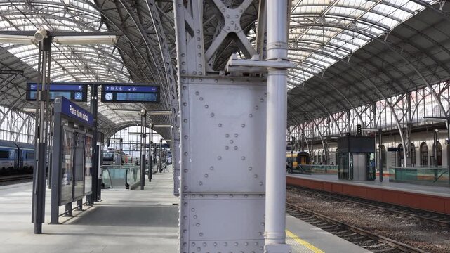 Modern European railway station with steel columns empty platforms and large glass roof creating clean urban transportation atmosphere during daylight travel hours