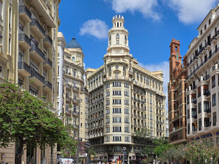Fototapeta premium Wide view of Plaza del Ayuntamiento in Valencia, Spain, with pedestrians strolling between ornate buildings. The scene shows Valencia central square and architecture.