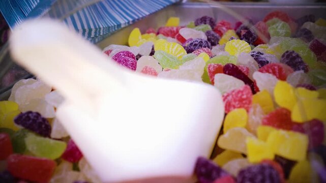 Saure Fruchtgummis in Verkaufsbox mit Sch&ouml;pfkelle auf Marktstand