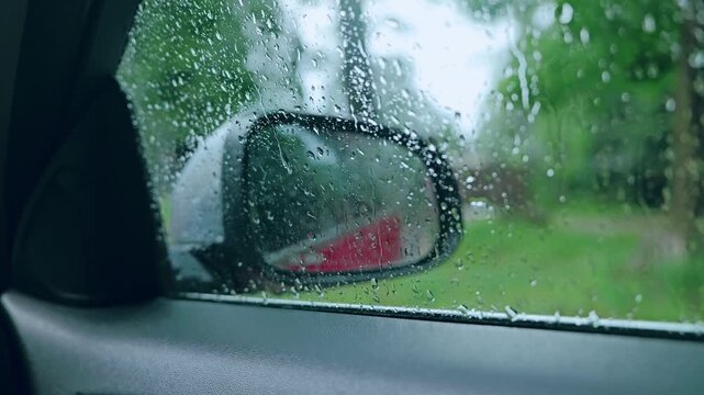 Static frame of rainy car window with water drops and mirror reflection