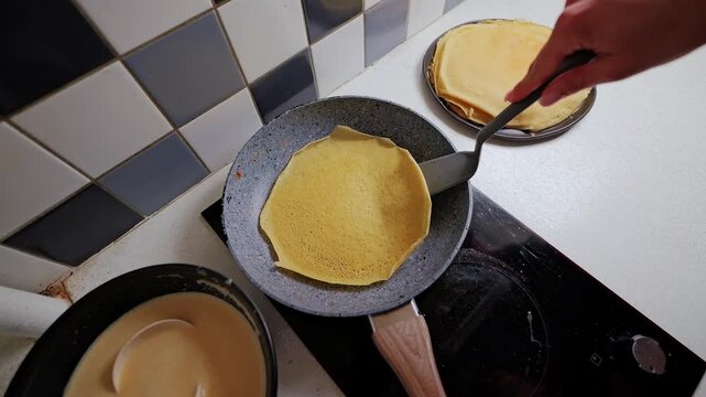 Woman flips crepe in pan with spatula showing precise movement in slow motion