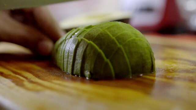 Slow-Motion Closeup of Chef Cutting Green Avocado to make Salpcion with a Sharp Cutlery Knife on Wooden Cutting Board