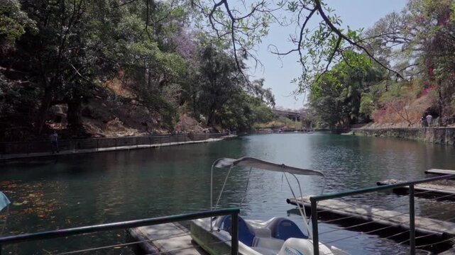 Calm lake with a small docked pedal boat and surrounding trees near a butterfly sanctuary in Mexico