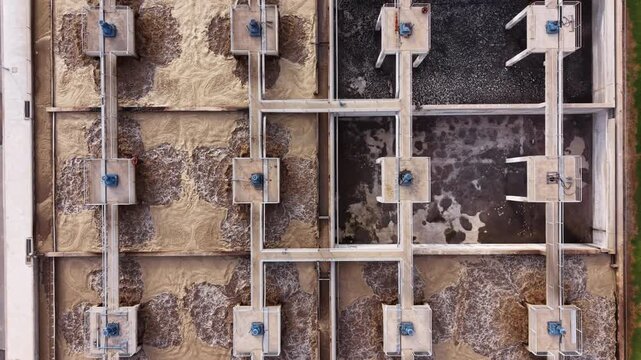 Top-down view of municipal wastewater treatment facility showing multiple bioreactor aeration basins with surface aerators, activated sludge process, biological oxygen demand treatment tanks