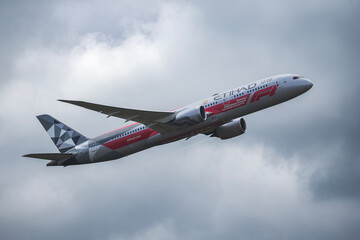 Fototapeta premium PRAGUE, CZECH REPUBLIC – MAY 06, 2026: Etihad Airways Boeing 787-9 Dreamliner Abu Dhabi Grand Prix Livery REG: A6-BLV in Flight Against Cloudy Sky