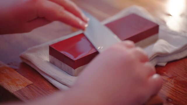Close up shot of person using a whetstone to sharpen a chef&rsquo;s knife