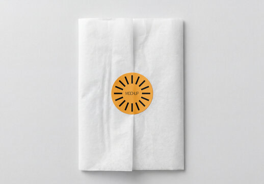 Top View of White Tissue Paper Wrap Mockup with Round Orange Sticker Seal for Branding and Gift Packaging Showcase