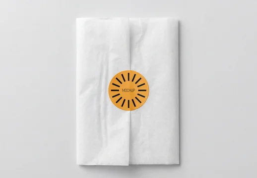 Top View of White Tissue Paper Wrap Mockup with Round Orange Sticker Seal for Branding and Gift Packaging Showcase