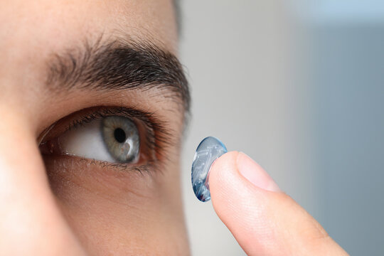 Contact lenses of future. Man putting lens with digital implants in her eye, closeup