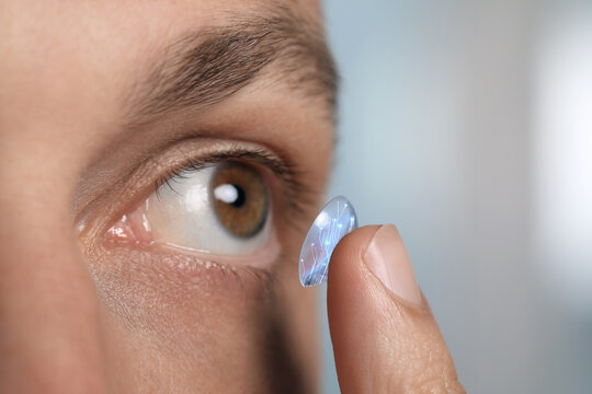 Contact lenses of future. Man putting lens with digital implants in her eye, closeup