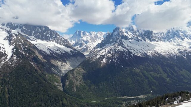 Epic aerial drone view of the Mer de Glace glacier flowing through the rugged alpine mountains near Chamonix, France, with towering snowy peaks and dramatic landscapes of the Mont Blanc massif capture