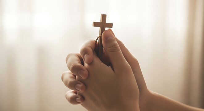 Hand holding small wooden Christian cross.