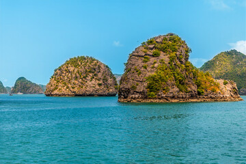 Naklejka premium A view from a cruise ship sailing past Karst limestone islets in Ha Long Bay, Vietnam on a bright sunny day