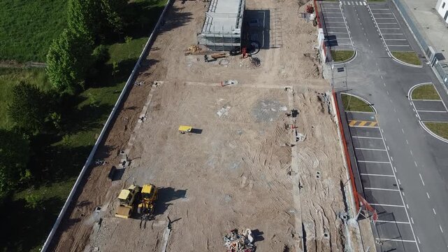 Aerial view of a construction site with heavy machinery and building foundations under development.