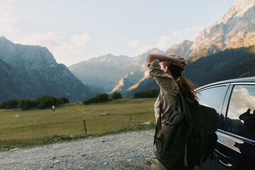 Naklejka premium Woman hiking through a mountainous landscape with a backpack beside a parked car, embodying exploration, adventure, and outdoor freedom in wide open scenery.