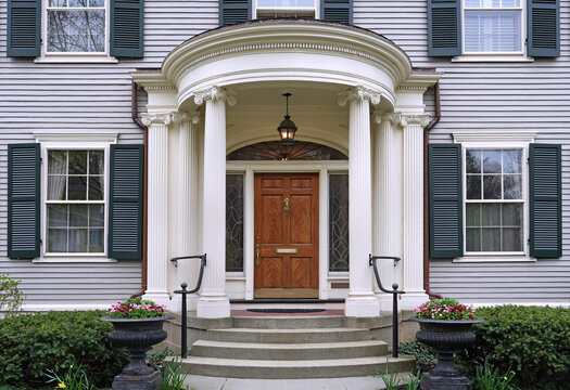 Elegant wood grain front door of grey clapboard house with round portico entrance