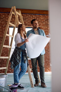 Happy couple going through blueprints in their renovating house.