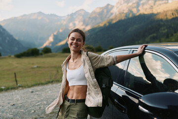 Naklejka premium Woman enjoying outdoor lifestyle beside a car in mountain landscape, smiling confidently, wearing casual hiking attire, sunlit scenery and sense of adventure