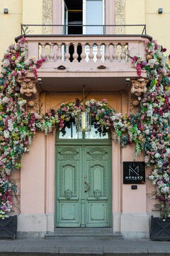 Vilnius, Lithuania - September 23 2025: Elegant floral-covered entrance of Monako Restaurant captured on a clear sunset evening. Pastel fa&ccedil;ade, ornate balcony and lush hydrangea arch 