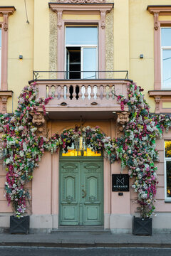 Vilnius, Lithuania - September 23 2025: Elegant floral-covered entrance of Monako Restaurant captured on a clear sunset evening. Pastel fa&ccedil;ade, ornate balcony and lush hydrangea arch 