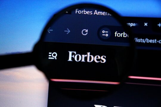 Salvador, Brazil - May 8, 2026: Forbes logo seen through a magnifying glass. Forbes website. Forbes is a leading American business magazine and global media brand. 