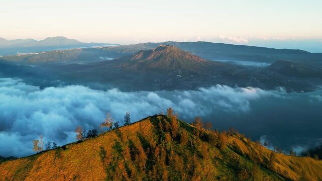 Mountain peak with golden morning light over grassy ridge and crater lake in volcano landscape in scenic highland terrain forward moving aerial drone footage