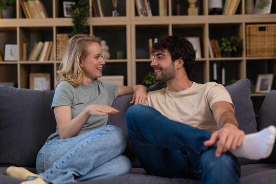 Happy couple talking and smiling on sofa at home