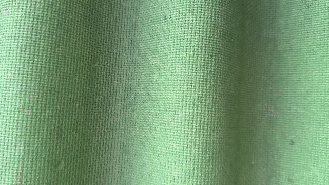 Green corrugated roofing tile closeup showing wavy fibrous surface and weatherproof bitumen texture, macro studio lit study