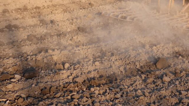 Macro of harrow plowing dry soil at sunset, farming background