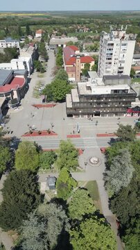 Vertical aerial shot of Vrbas, Serbia. Drone features a lateral side-glide movement over the central urban area on a bright sunny day. Focus on town architecture and street layout.