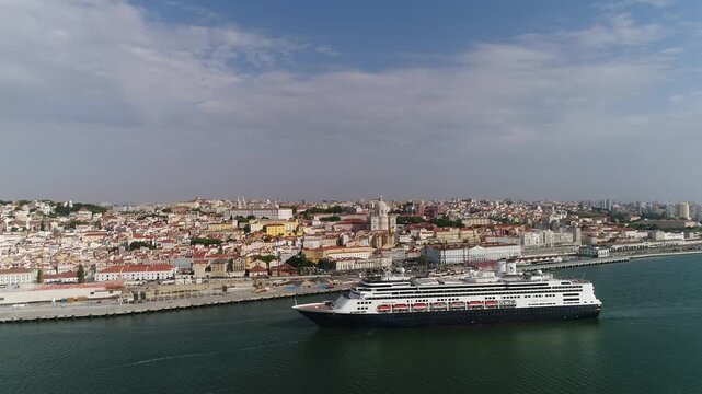 Cruise boat on the banks of the Tejo River with the historic city of Lisbon in the background.