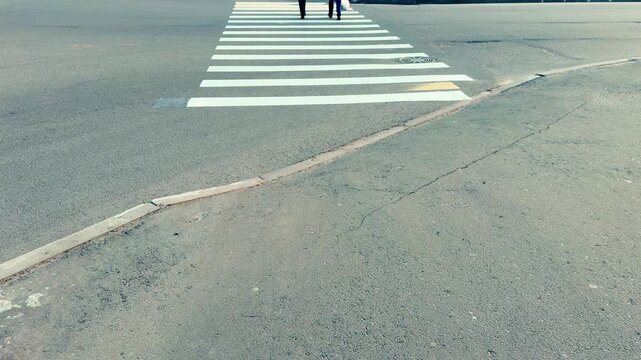 Rear view pedestrians crossing zebra crosswalk quiet urban street textured asphalt faded stripes two figures walking away daytime