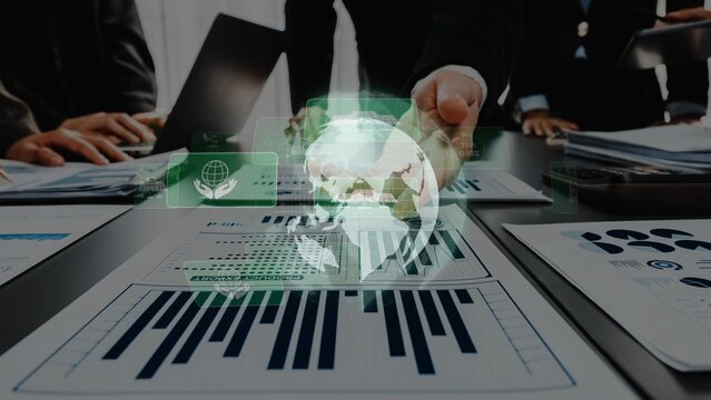 A business team engages in strategic planning and analysis using financial charts and digital overlays, capturing global market trends in a modern office setting. Raster