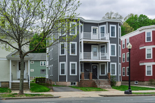 Traditional New England triple decker residential building with updated gray vinyl siding in the Brighton neighborhood of Boston, Massachusetts, USA