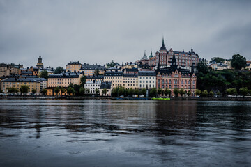 Obraz premium Stockholm Sweden Södermalm Waterfront with Historic Münchenbryggeriet Building and Boat on Calm Water Under Overcast Sky