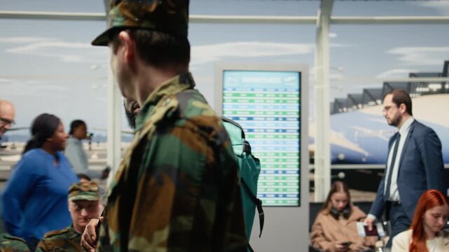 Men in army squad navigating busy airport terminal hallway, travelling home to see family. Soldiers carrying rucksack toward airplane boarding gate after finishing active military duty, camera A