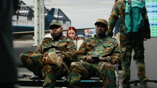 Army men in airport departure lounge looking at flight status display timetable. Military squad reading electronic departure board schedule, waiting for plane arrival, camera A