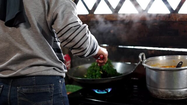 A vendor cooks stir-fried bracken for customers. Indonesian street food.
