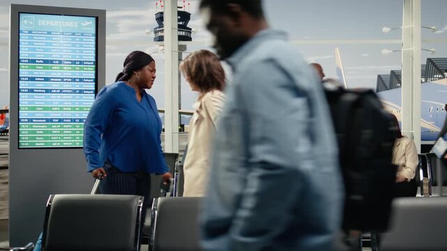 Woman in crowded airport annoyed by flight delay during international holidays season. Tourist looking at boarding gate number on screen in busy transportation hub to catch plane, going home, camera A