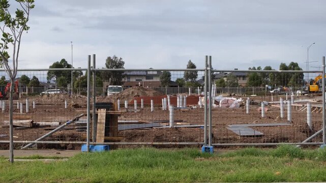 Construction site with temporary fencing and foundation pillars in Tarneit, Melbourne Australia. A new housing project showcasing land development, residential infrastructure growth, civil engineering