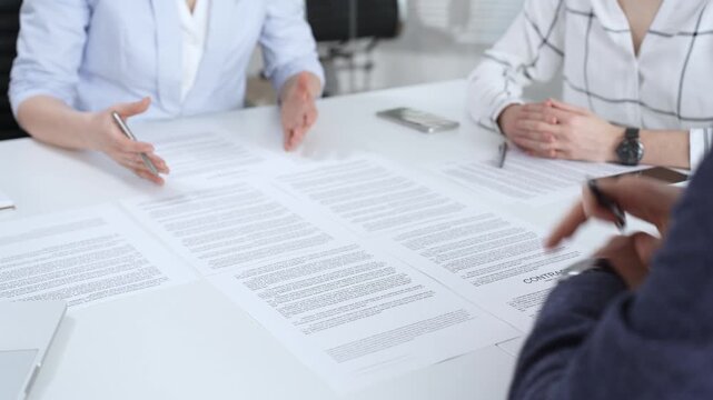 Business people discussing contract terms, outlining agreements, and reviewing legal documents during a corporate meeting, preparing for a significant partnership signing and negotiation