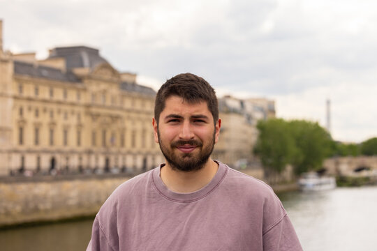Portrait d&rsquo;un jeune homme souriant au bord de la Seine &agrave; Paris avec architecture historique en arri&egrave;re-plan