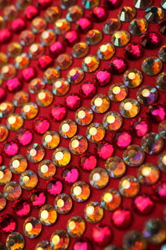 Sparkling pink and iridescent rhinestones on red fabric background